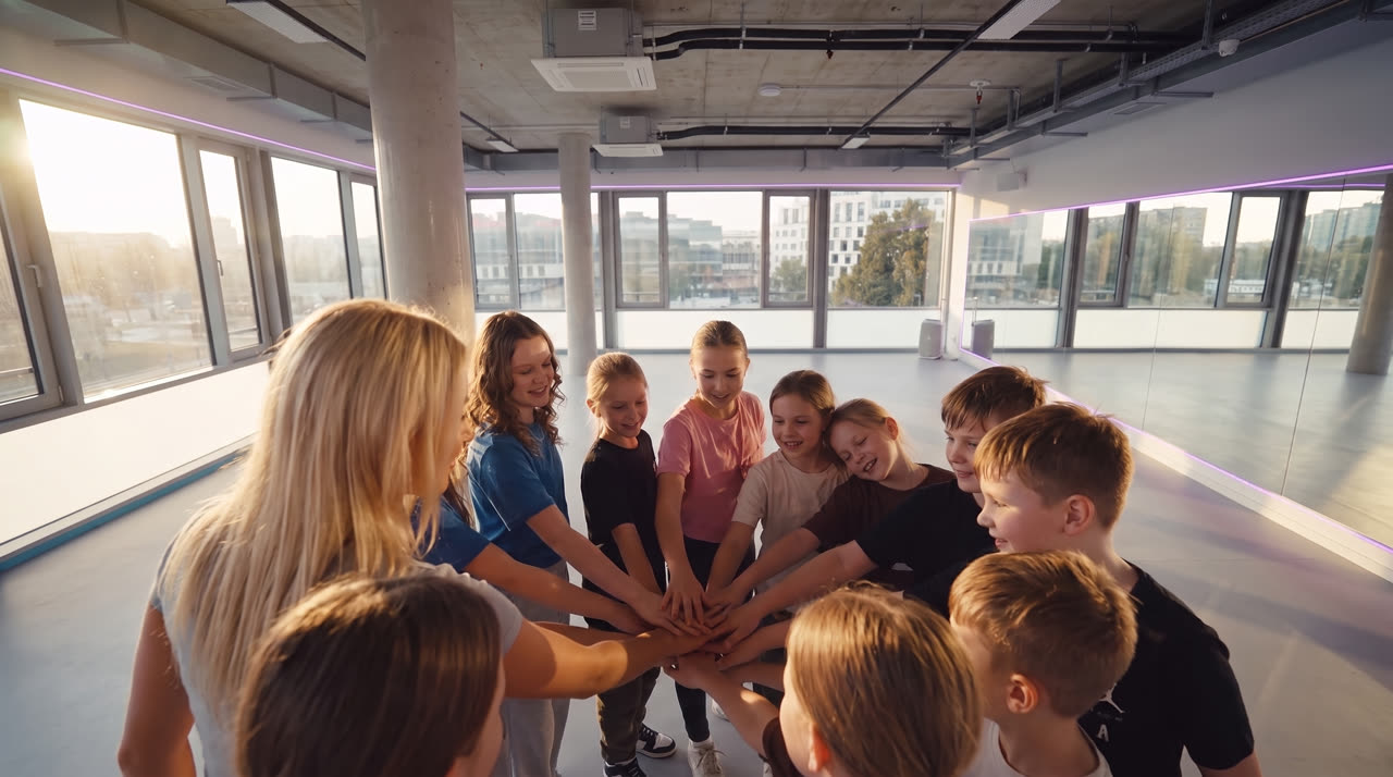 Schulklasse und Coach stehen im Kreis, alle Hände in der Mitte